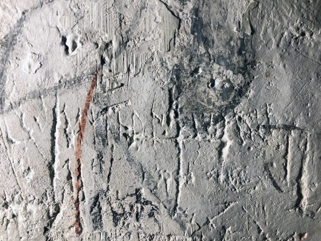 Bilden visar runor och andra ristningar på en kyrkvägg