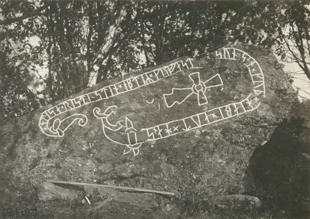 Bilden föreställer en liggande runsten fotograferad i svartvitt.