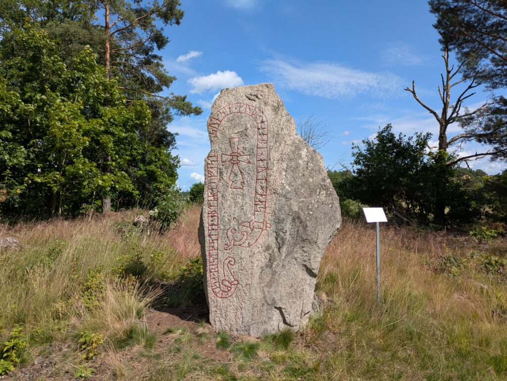 Bilden visar en runsten uppmålad med rött.
