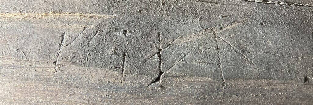 Närbild på en träbild med ett par runor på.