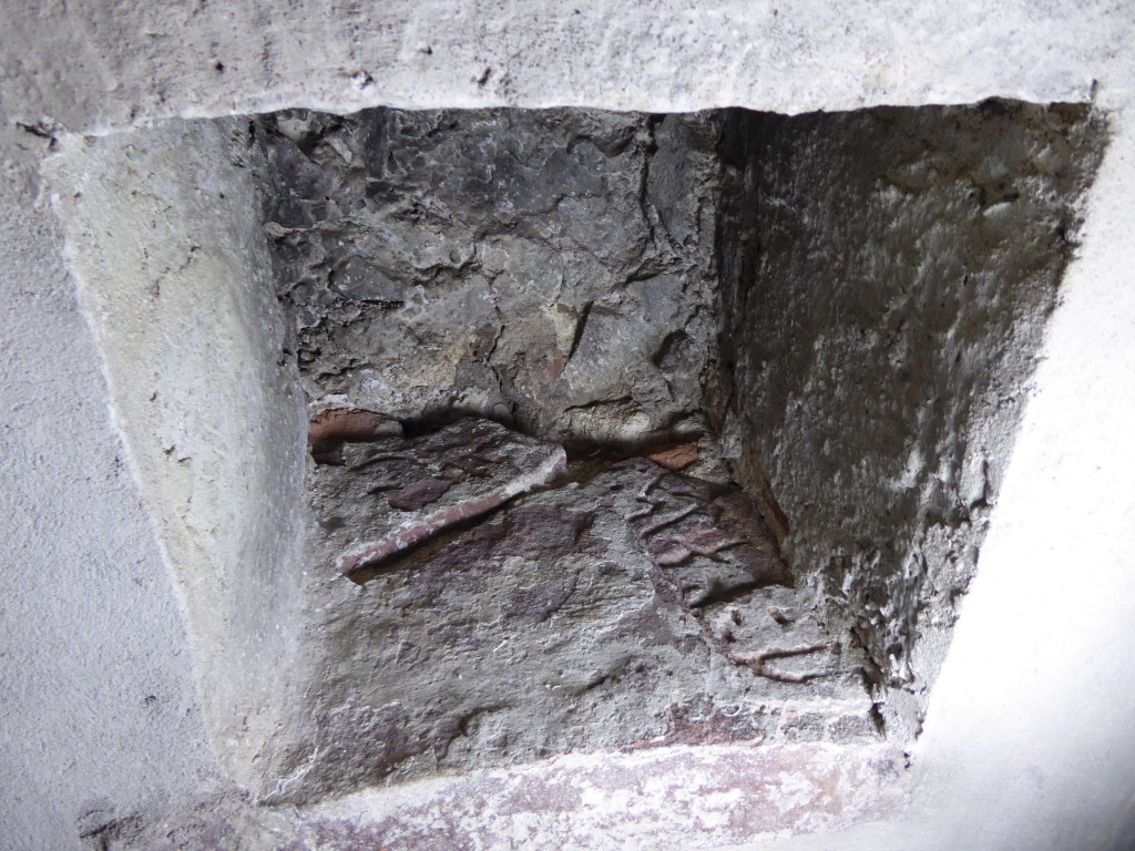 Bilden visar ett par runstensfragment som ligger som ligger som botten i en väggnisch