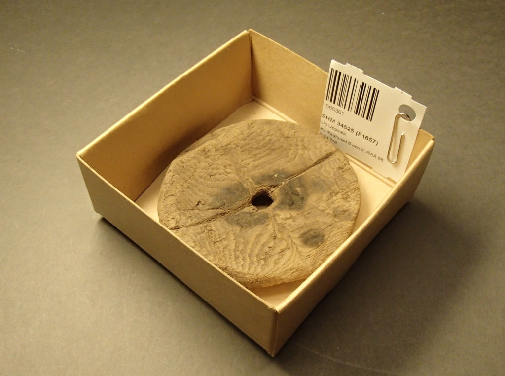 Bilden visar ett runt träföremål i en fyndask