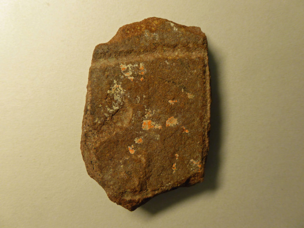 Bilden visar ett litet runstensfragment med två runor