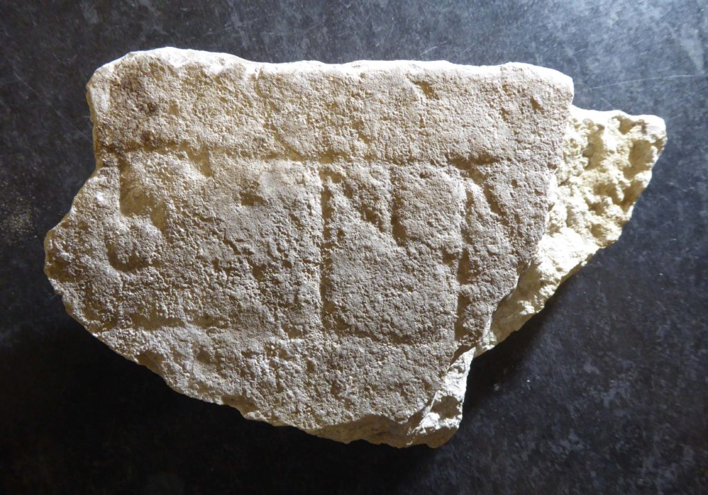 Bilden visar ett fragment av kanten av en runristad gravhäll av kalksten