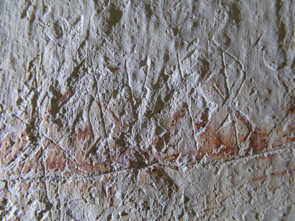 Bilden visar runor ristade i kalkputs på en kyrkvägg