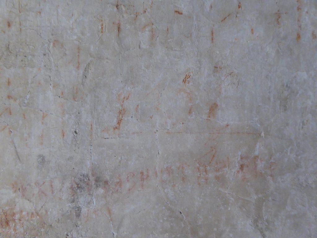 Bilden föreställer nästan helt utplånade runor skrivna med rödkrita på en kyrkvägg