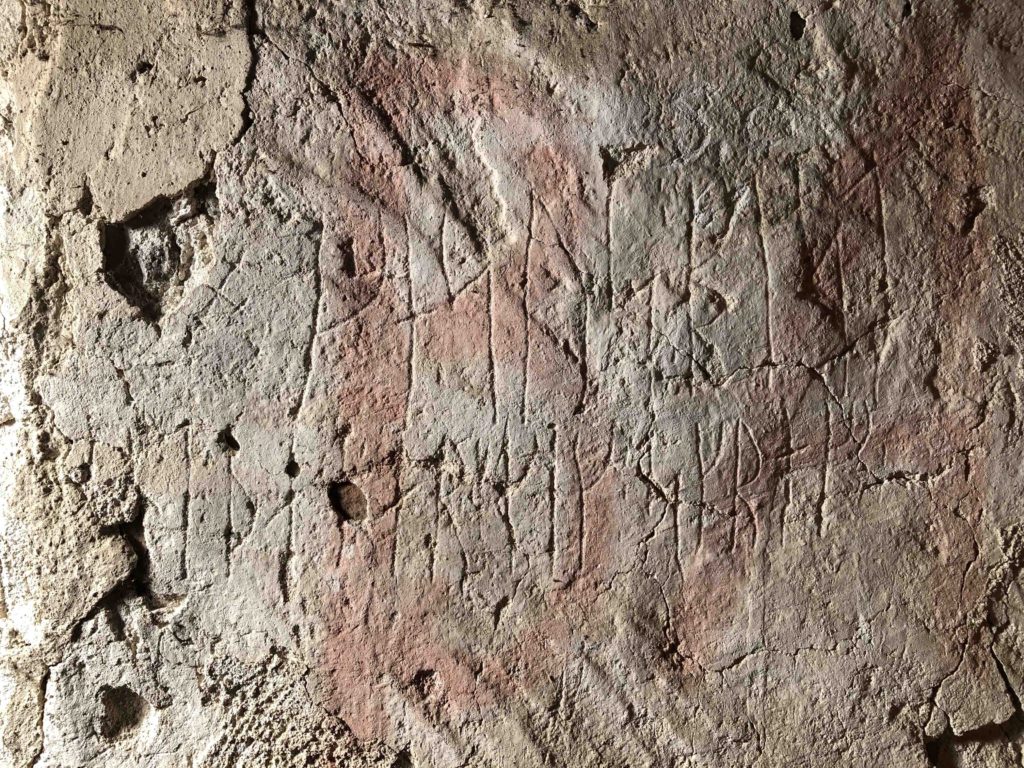 Bilden visar två rader med runor ristade i kalkputs