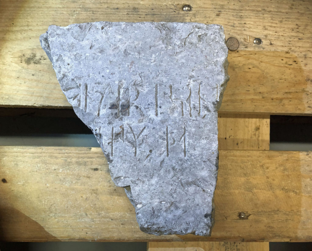 Bilden visar ett kalkstensstycke med runor på en lastpall