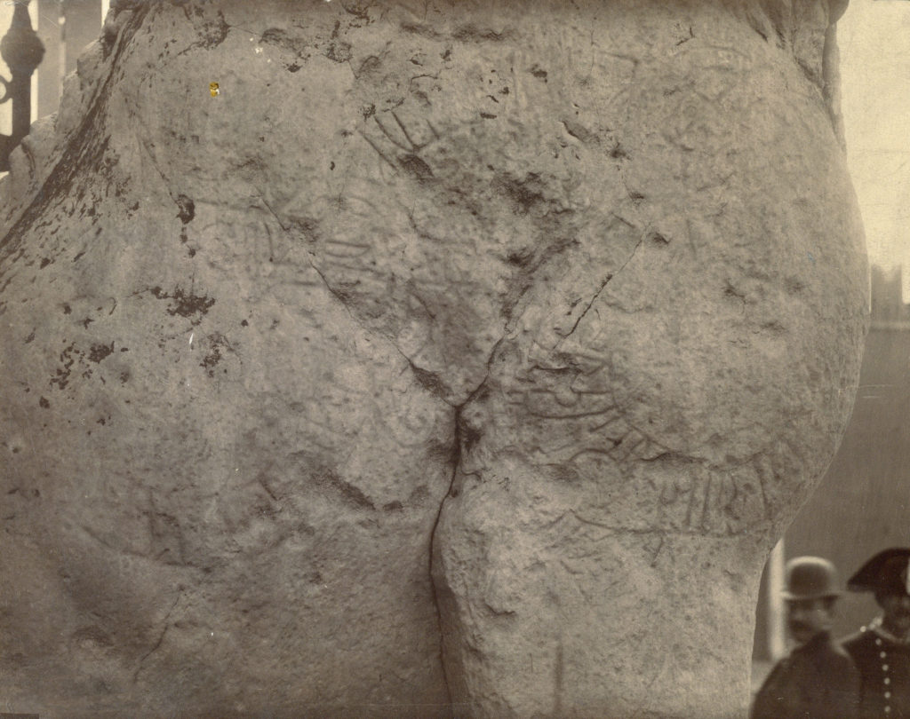 Bilden visar en närbild av runorna på marmorlejonets ena sida