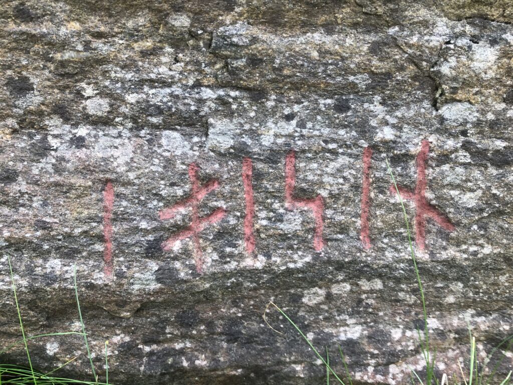 Bilden visar en detalj av stenen med sex runor uppmålade med röd färg