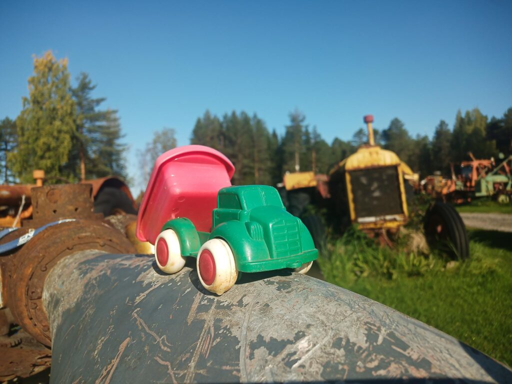 Holgers traktormuseum; ett utomhusmuseum med veterantraktorer i bakggrunden, och en liten leksakslastbil av plast i förgrunden.