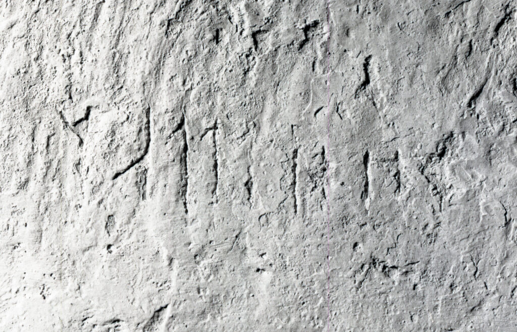 Bilden visar en rad med runor ristade i puts.