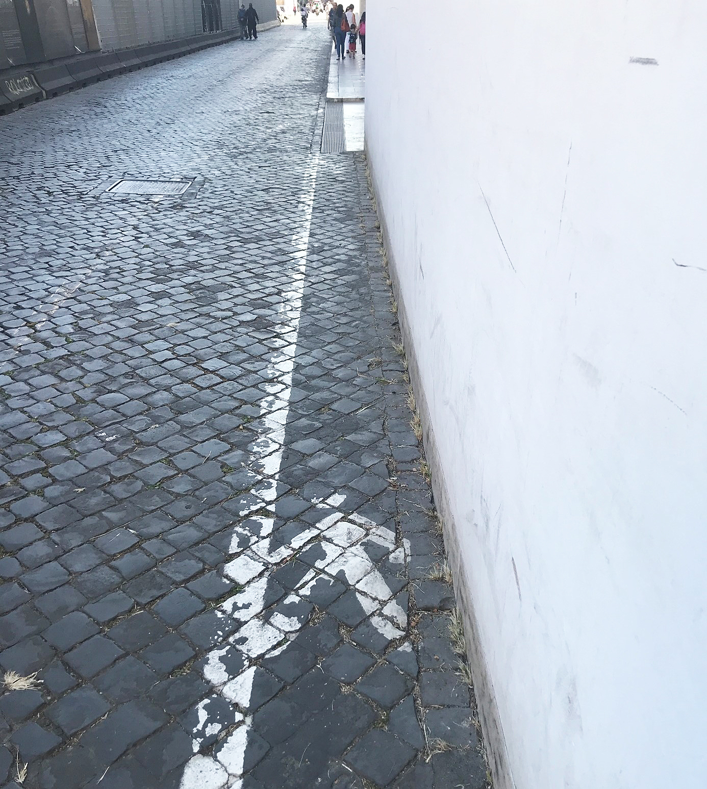 Bild av stenlagd trottoar med vit målad linje och streckgubbe som visar gångfältet på Via di Ripetta, vid Museo dell’Ara Pacis i Rom.