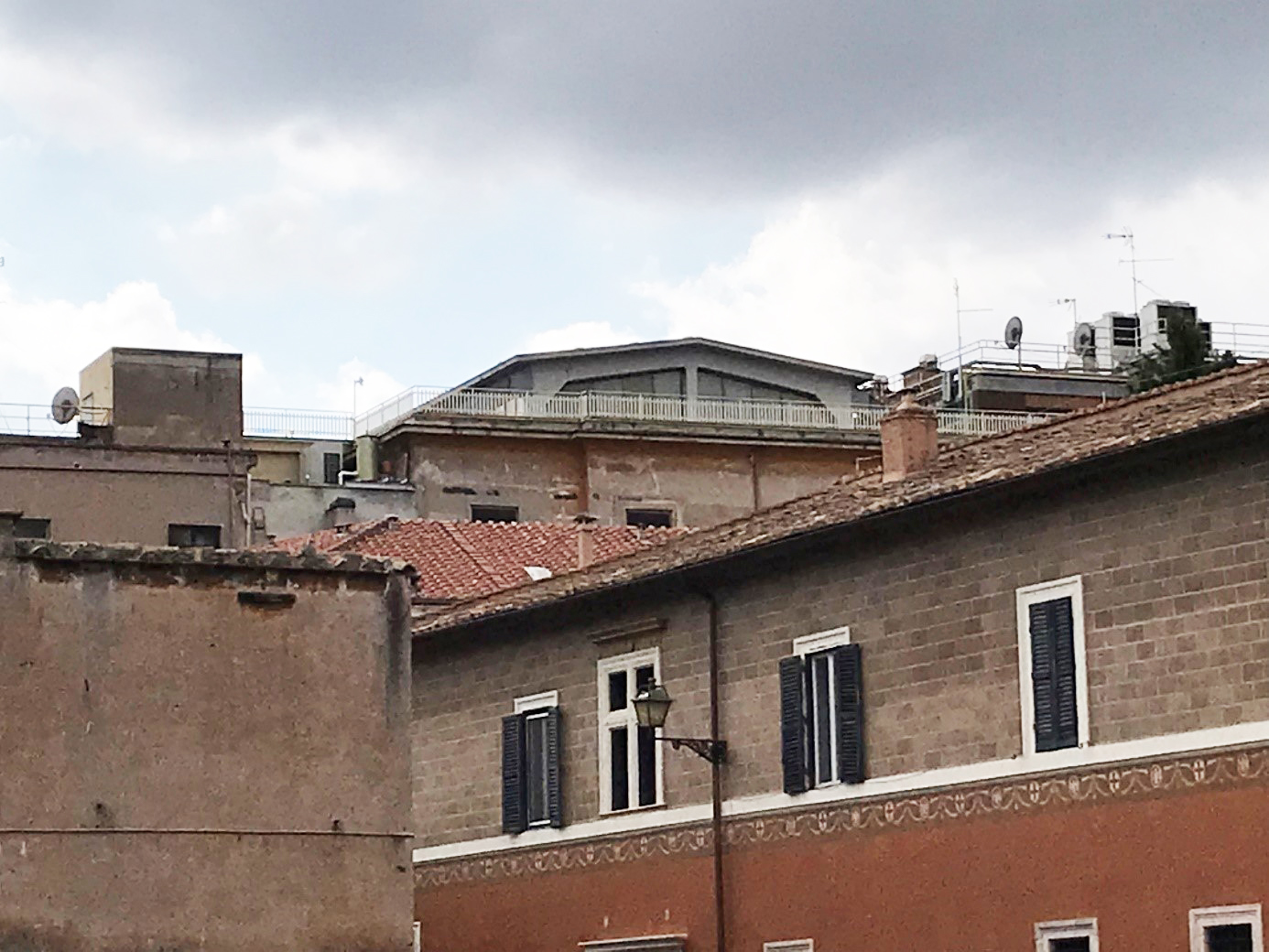 Bild av ett taklandskap i stadsdelen Trastevere i Rom. Tegelfasader, fönster, fönsterluckor, terrasser, antenner.