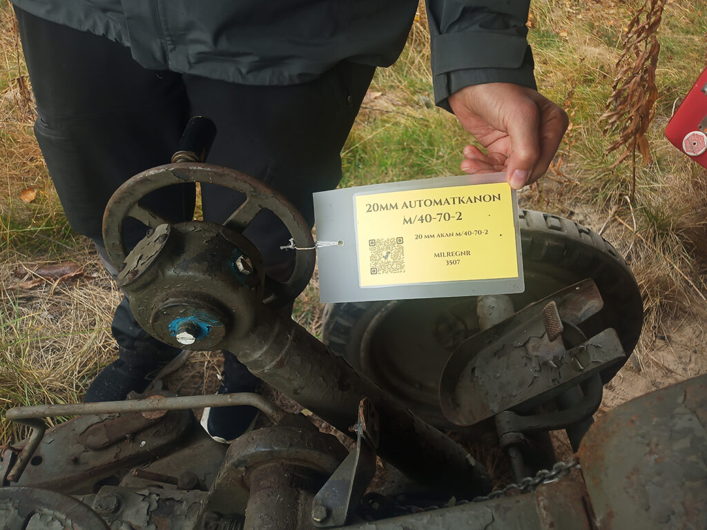 En gul, laminerad skylt med QR-kod ger mera information om en 20 mm automatkanon M/40-70-2.